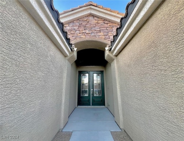 view of exterior entry featuring french doors and stucco siding