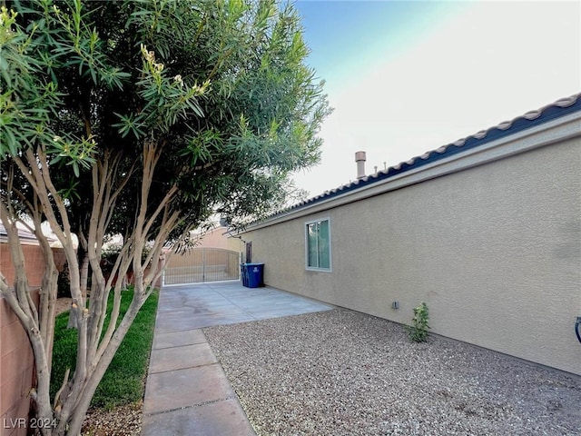 view of side of home featuring a patio area, fence, a gate, and stucco siding