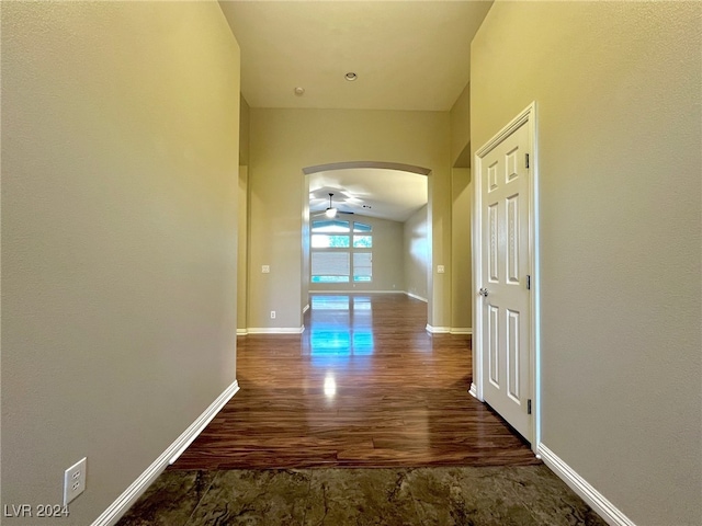 hallway with dark hardwood / wood-style floors and vaulted ceiling