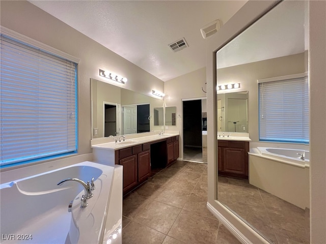 bathroom featuring vanity, vaulted ceiling, a bath, and tile patterned floors