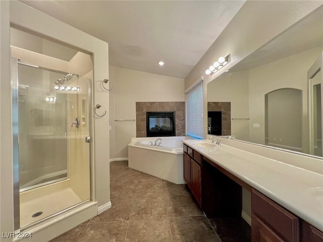 full bathroom with a fireplace, a shower stall, a bath, a sink, and double vanity
