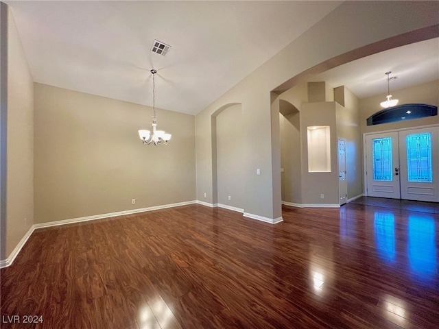 unfurnished room featuring lofted ceiling, an inviting chandelier, and dark hardwood / wood-style flooring