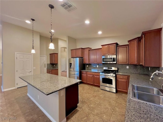 kitchen featuring appliances with stainless steel finishes, a kitchen island, visible vents, decorative backsplash, and a sink