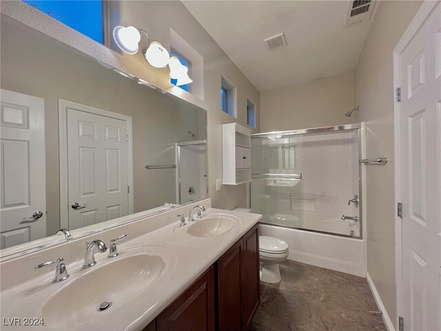 full bathroom featuring toilet, combined bath / shower with glass door, and vanity