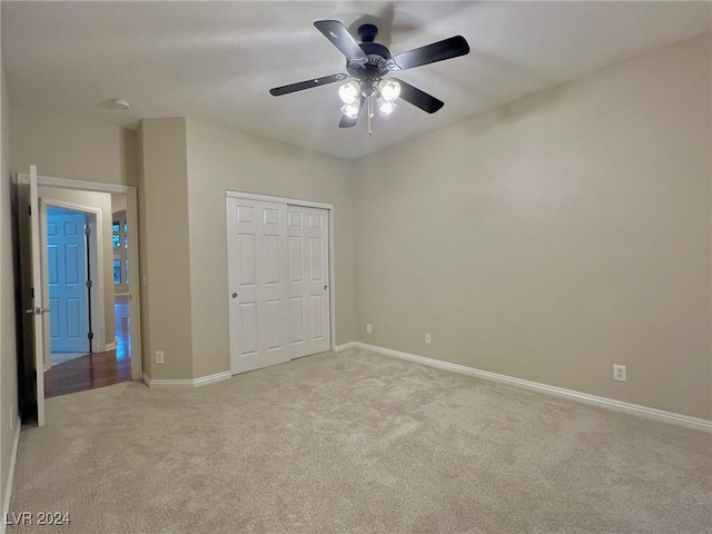 unfurnished bedroom with a closet, baseboards, ceiling fan, and light carpet