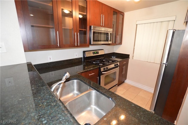 kitchen featuring dark stone countertops, light tile patterned floors, sink, and appliances with stainless steel finishes