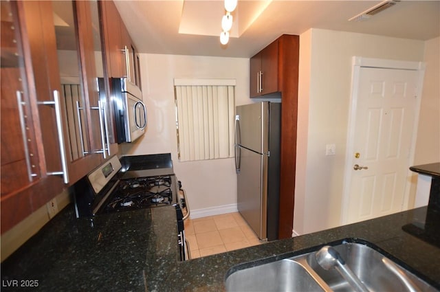 kitchen with dark stone counters, light tile patterned floors, and stainless steel appliances