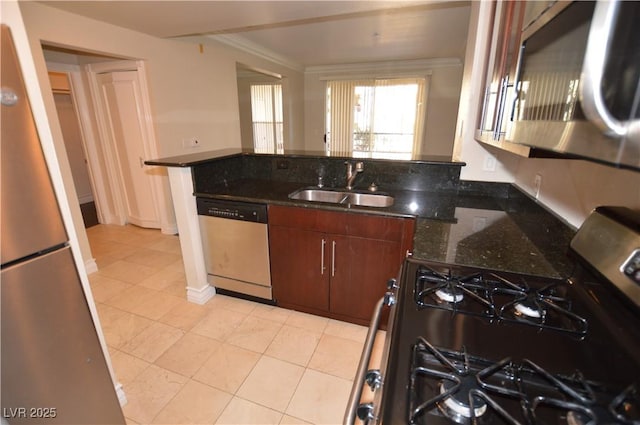 kitchen featuring appliances with stainless steel finishes, ornamental molding, sink, light tile patterned floors, and dark stone countertops