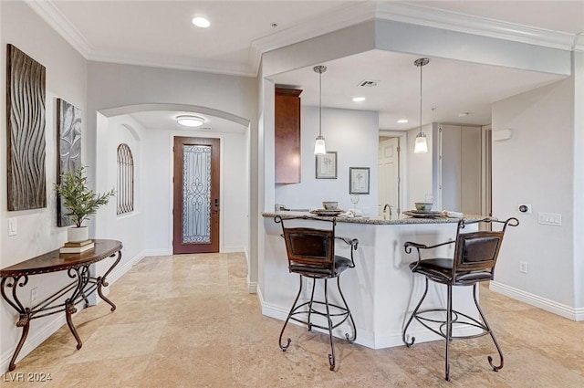 kitchen with hanging light fixtures, a breakfast bar, arched walkways, stone counters, and baseboards