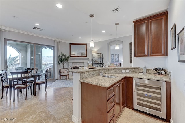 kitchen featuring decorative light fixtures, sink, kitchen peninsula, wine cooler, and ornamental molding