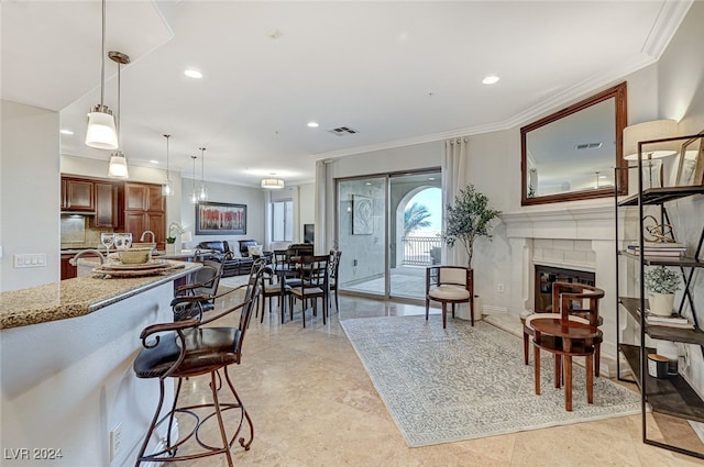 kitchen with ornamental molding, pendant lighting, a breakfast bar area, and light stone countertops