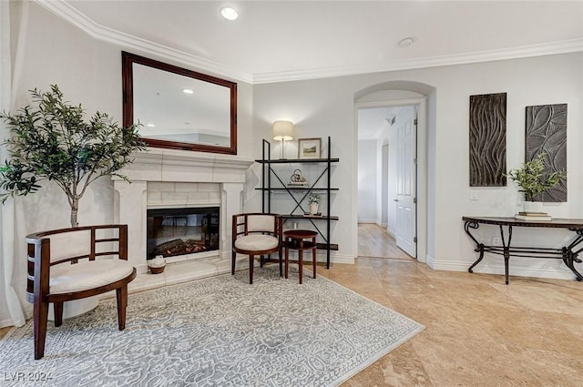 sitting room featuring arched walkways, a glass covered fireplace, baseboards, recessed lighting, and ornamental molding