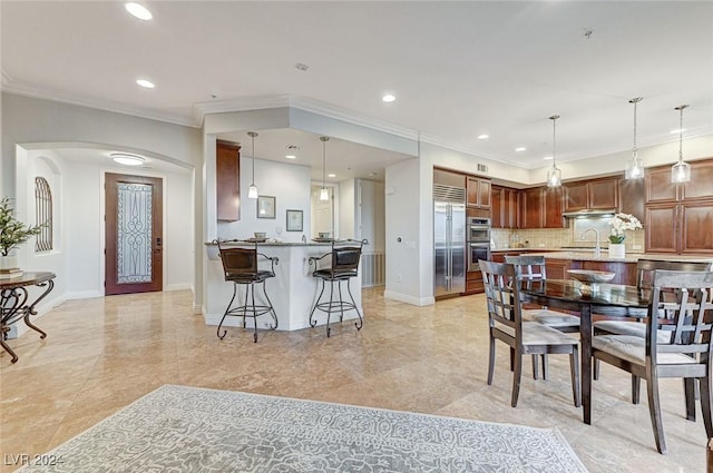 dining area featuring arched walkways, crown molding, baseboards, and recessed lighting