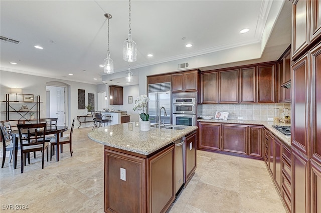 kitchen with pendant lighting, stainless steel appliances, crown molding, and a kitchen island with sink