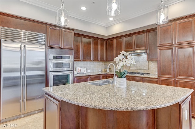 kitchen featuring decorative light fixtures, stainless steel appliances, a center island with sink, and ornamental molding