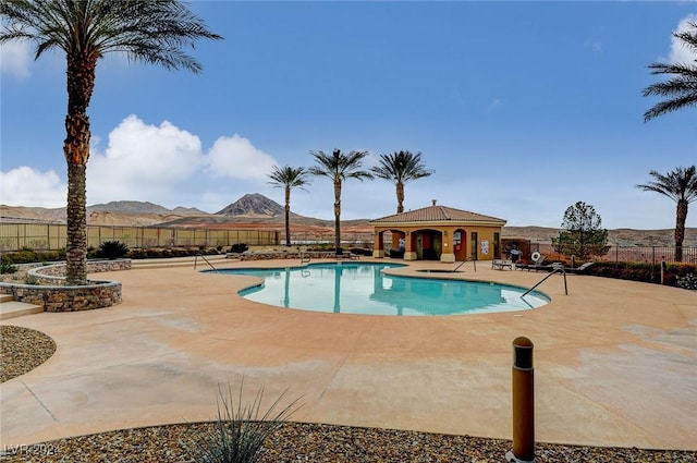 pool with fence, a patio, and a mountain view