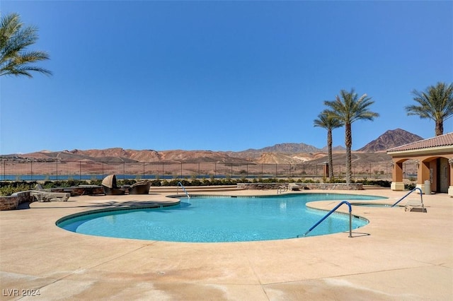 community pool with a patio area, fence, and a mountain view