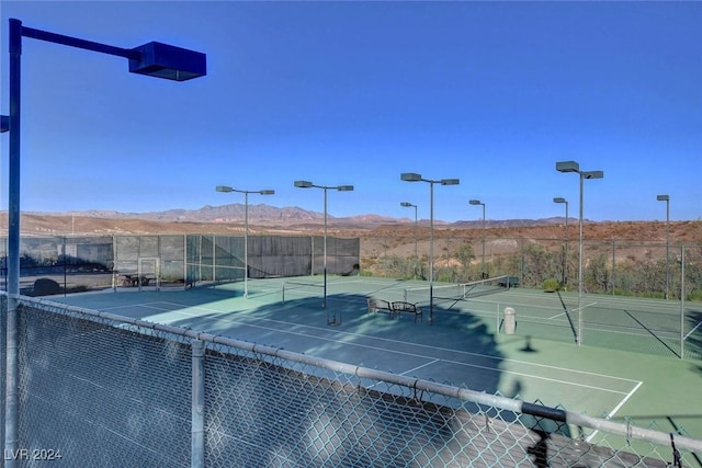 view of tennis court featuring fence and a mountain view