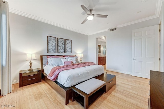 bedroom with light wood finished floors, visible vents, arched walkways, and crown molding