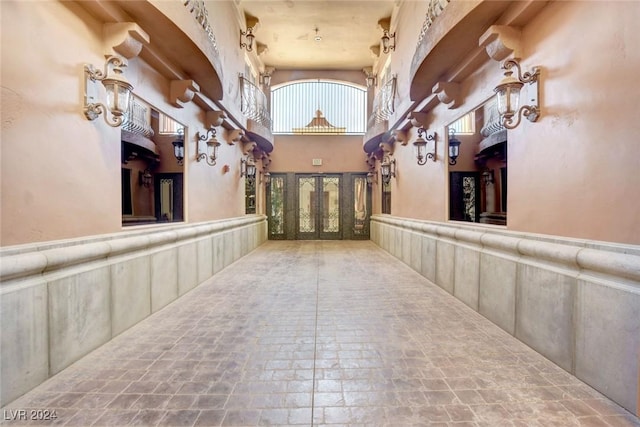 hall with wainscoting, stone finish flooring, and a high ceiling
