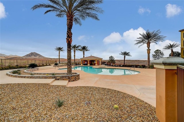 pool with a patio, fence, and a mountain view