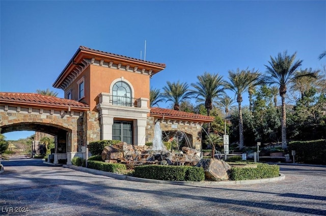 view of front of house featuring stucco siding, a tile roof, stone siding, and a balcony