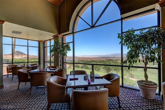 sunroom / solarium featuring a towering ceiling, carpet, and a mountain view