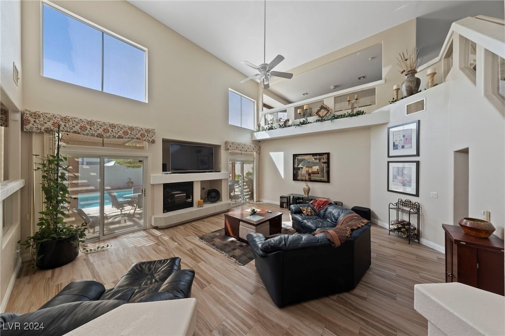 living room with hardwood / wood-style flooring, ceiling fan, and a towering ceiling