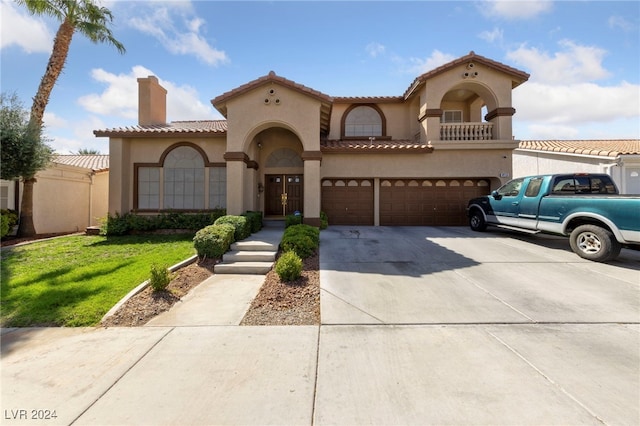 mediterranean / spanish-style house featuring a garage and a front lawn