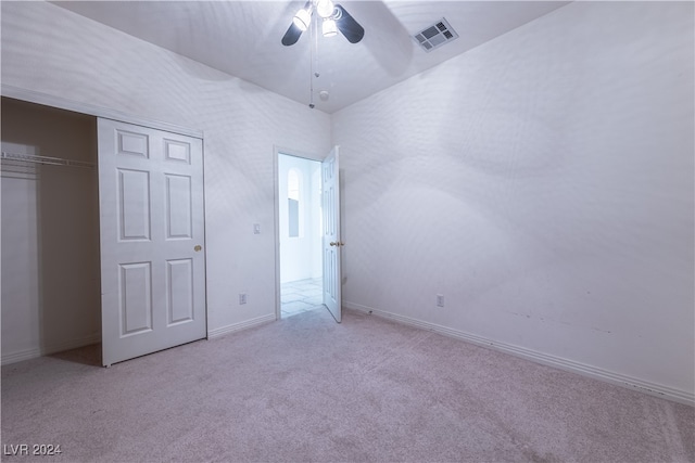 unfurnished bedroom featuring light carpet, a closet, lofted ceiling, and ceiling fan