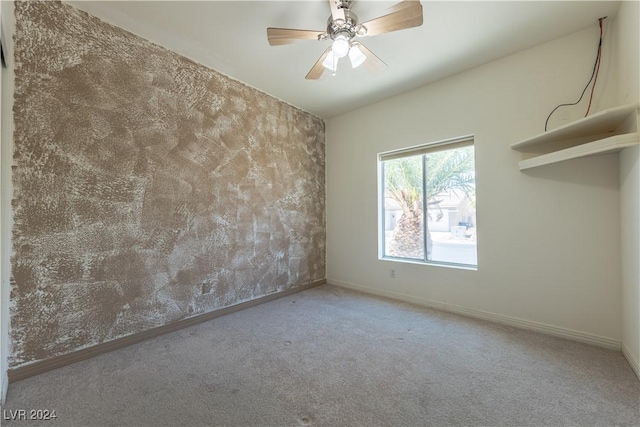 carpeted spare room featuring ceiling fan and baseboards