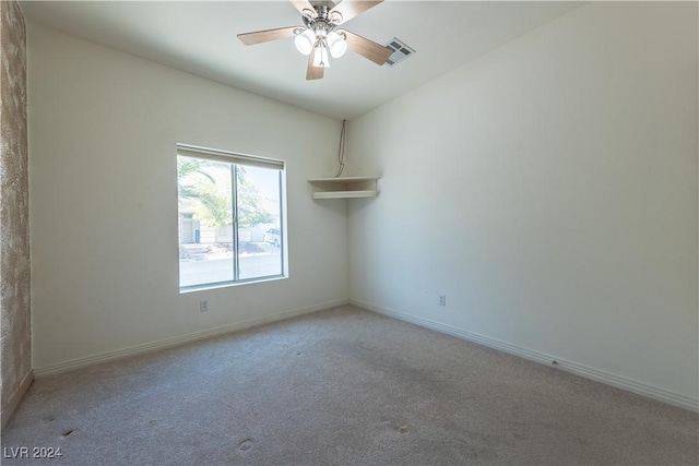 spare room with ceiling fan, light colored carpet, visible vents, and baseboards