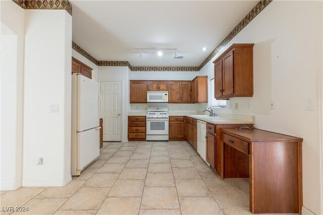 kitchen with white appliances, light tile patterned flooring, a sink, rail lighting, and brown cabinets