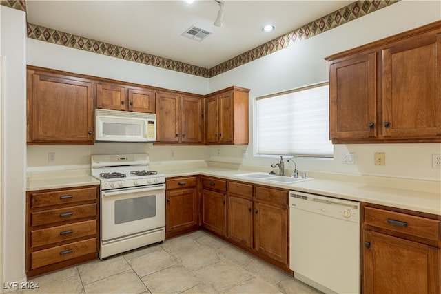 kitchen with white appliances, light tile patterned floors, and sink