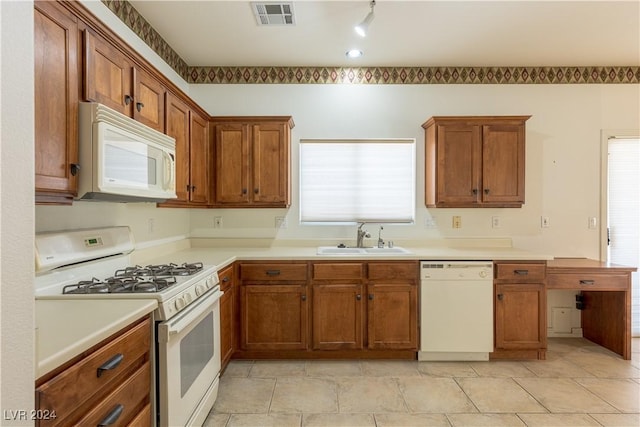 kitchen with white appliances, brown cabinets, visible vents, and a sink