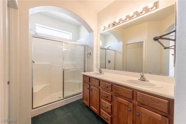 full bathroom featuring double vanity, a stall shower, and a sink