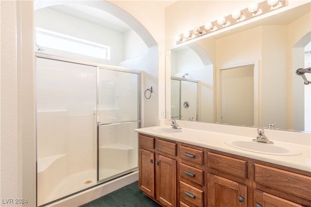 bathroom featuring a shower with door and vanity