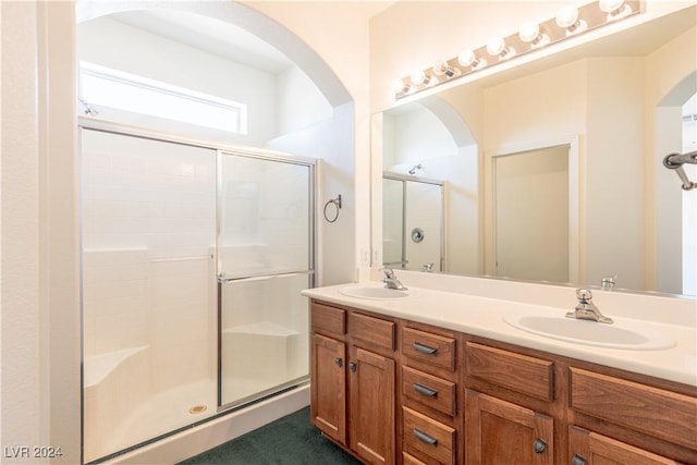 bathroom featuring double vanity, a stall shower, and a sink