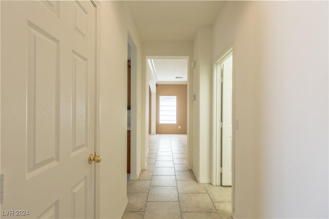 corridor with light tile patterned floors and crown molding