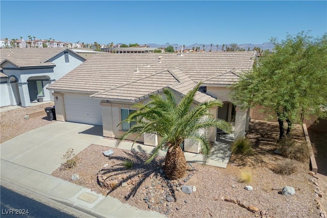 view of front facade with stucco siding, concrete driveway, an attached garage, and a tile roof