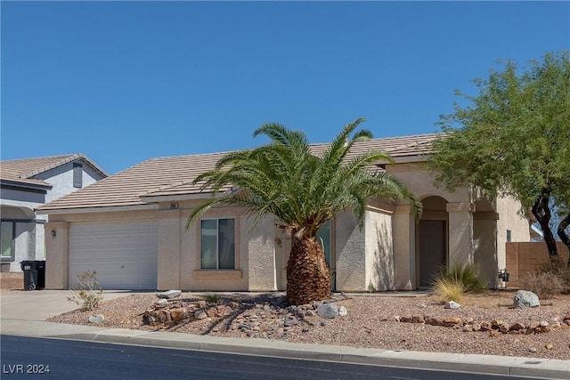 view of front of property featuring stucco siding, driveway, a tile roof, and a garage