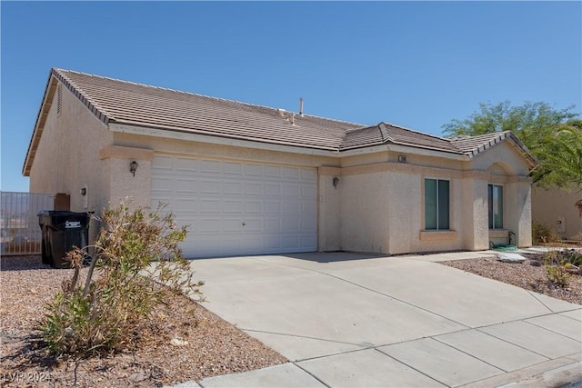 view of front facade with concrete driveway, a tiled roof, an attached garage, and stucco siding