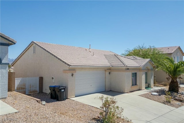 exterior space featuring fence, a tiled roof, concrete driveway, stucco siding, and a garage