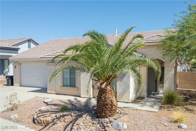 view of front of house with stucco siding, driveway, a tile roof, and an attached garage
