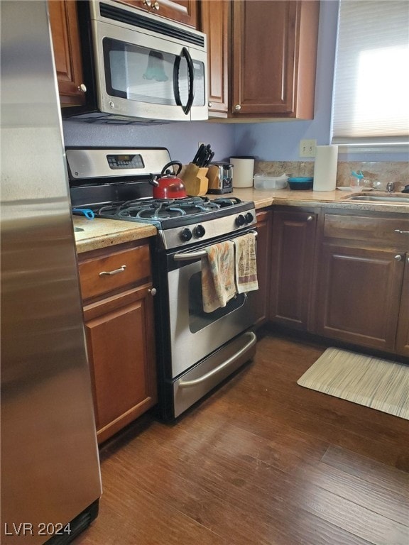 kitchen with stainless steel appliances, sink, and dark hardwood / wood-style flooring