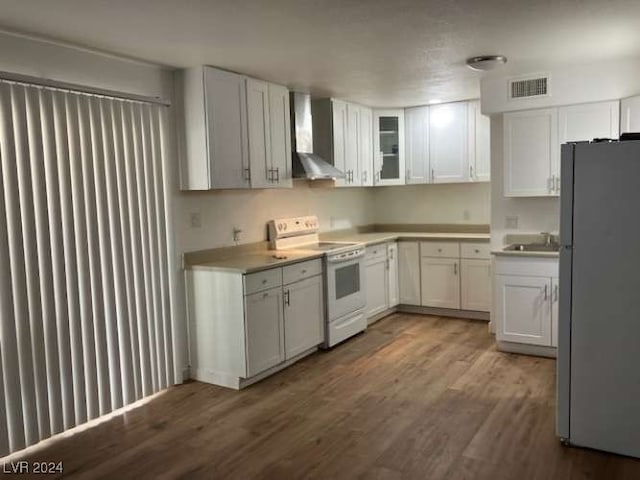 kitchen with wall chimney exhaust hood, white cabinetry, stainless steel refrigerator, white electric range, and dark hardwood / wood-style flooring