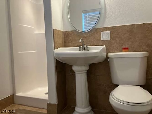 bathroom featuring tile walls, a shower, and toilet