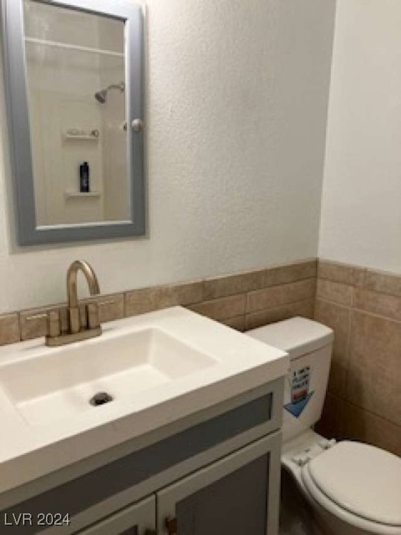 bathroom with vanity, tile walls, and toilet