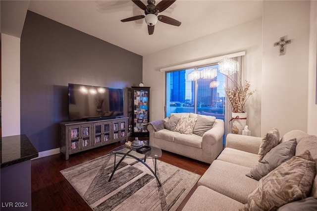 living room with a ceiling fan, dark wood-type flooring, baseboards, vaulted ceiling, and a chandelier