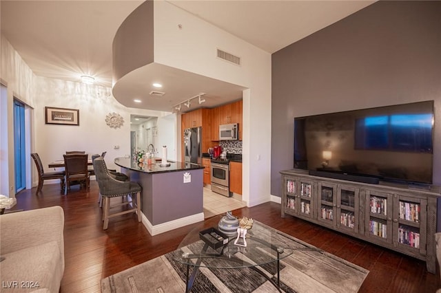 living area with wood finished floors, rail lighting, and baseboards
